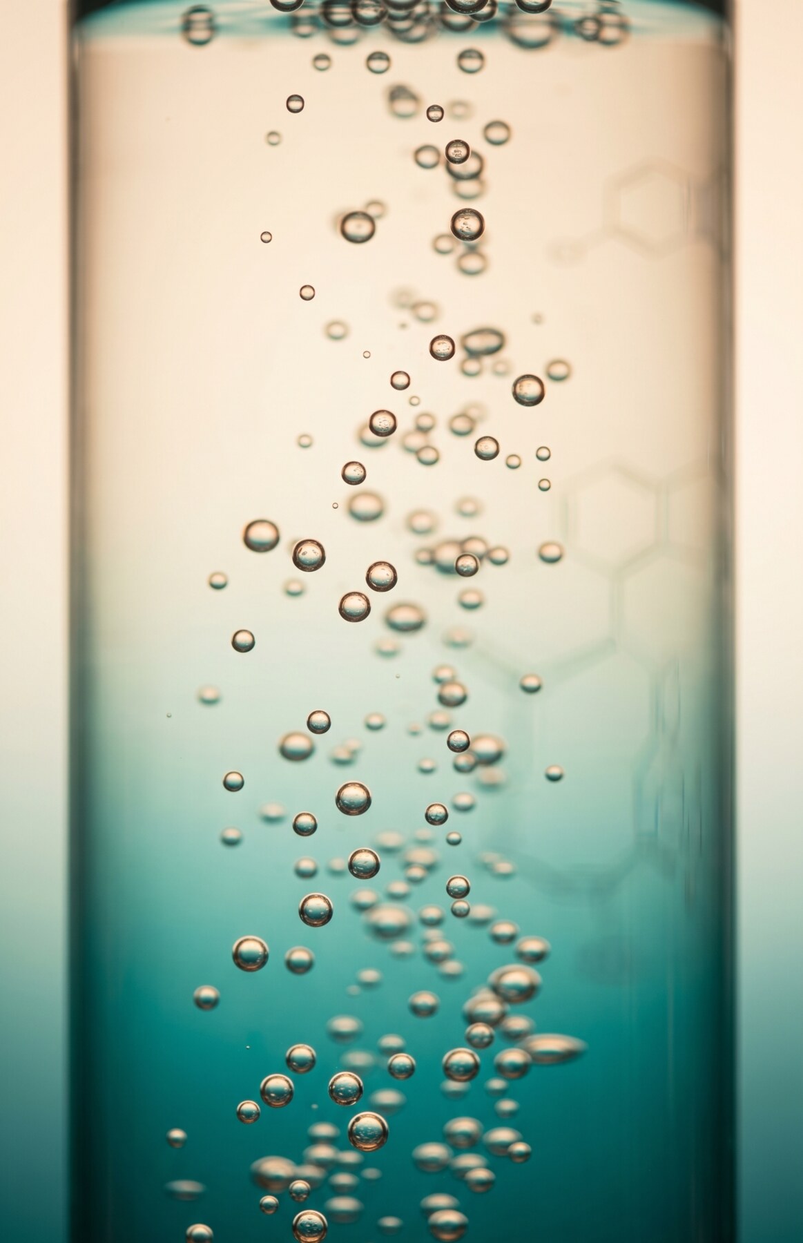 Backlit teal hydrogen bubbles rising through a tall glass vessel, warm to cool gradient