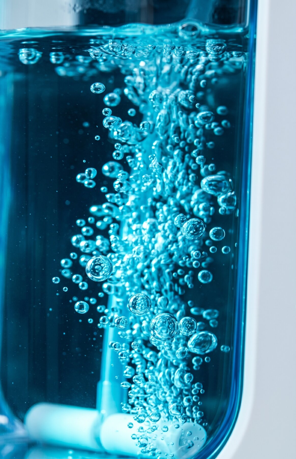 The Hydro Nova reservoir during electrolysis &mdash; fine teal hydrogen bubbles streaming through purified water under precise product lighting